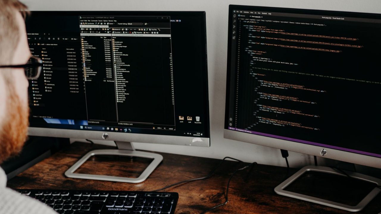 Developer auditing site code on dual monitors